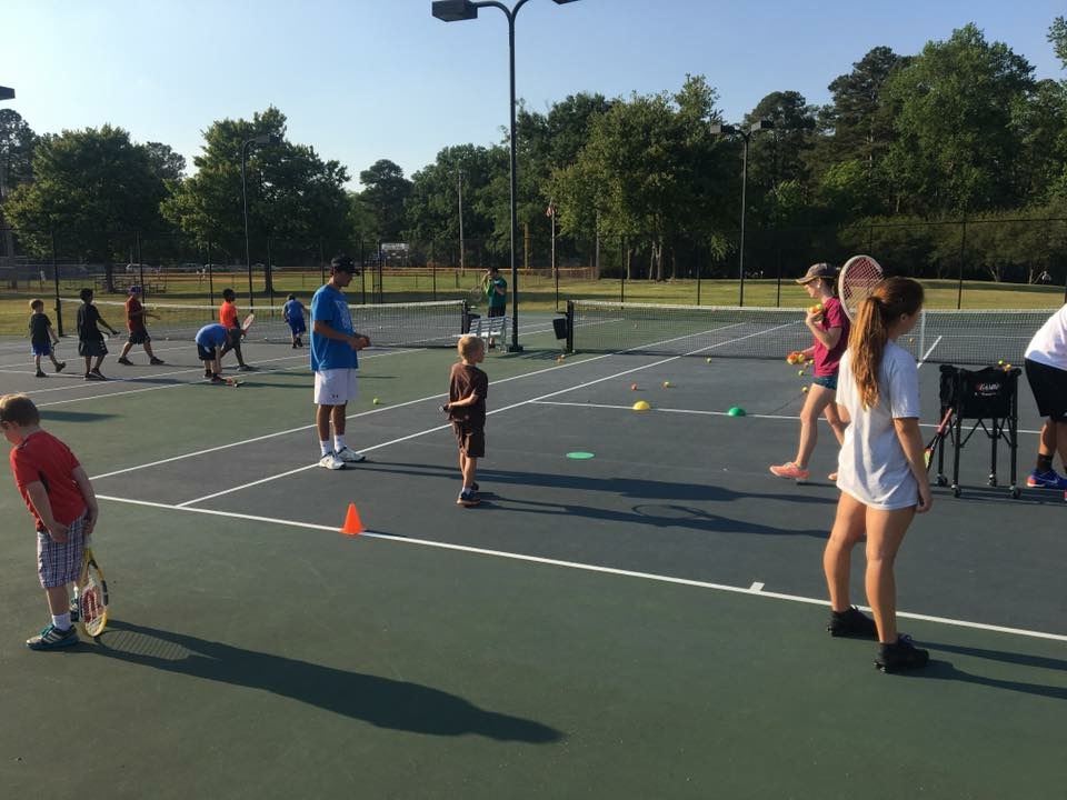 People playing tennis on tennis courts in the park